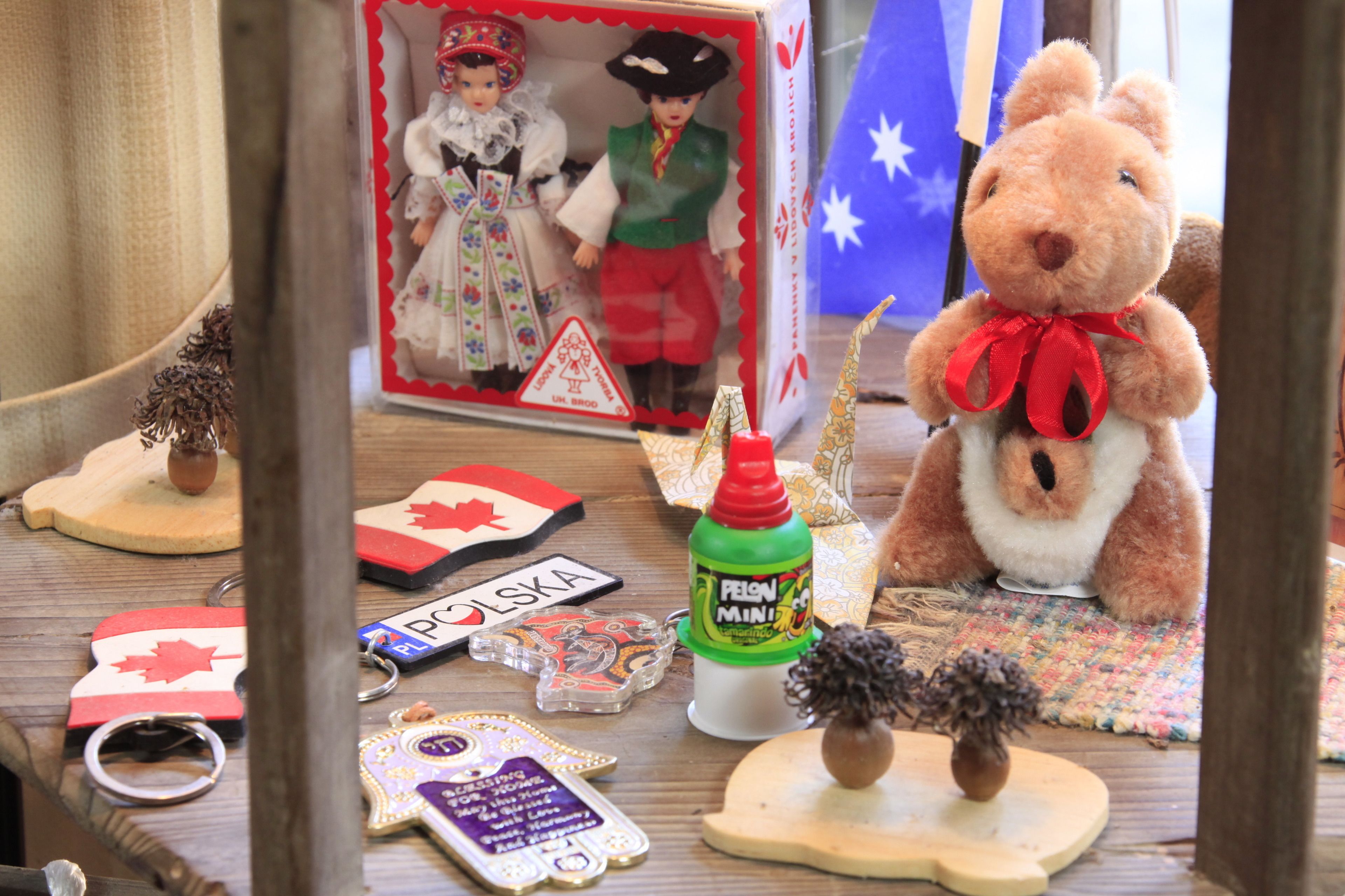 A table with various souvenirs, a stuffed bear, and a box with dolls.