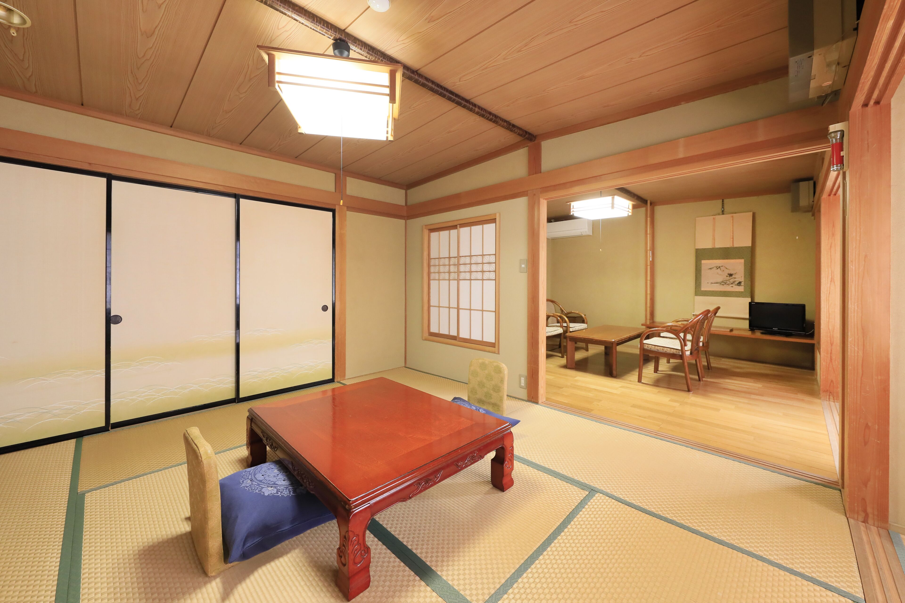 A traditional Japanese room with tatami flooring, a wooden table, and sliding doors.