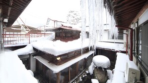 Un edificio tradicional de madera con fachada nevada y cascadas de hielo colgando del techo.
