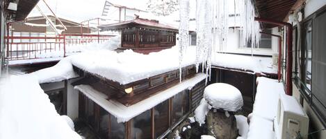 A traditional wooden building with snow-covered exterior and icicles hanging from the roof.