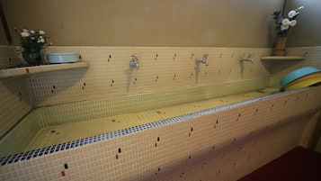 Un baño con suelo de azulejos, un lavabo y un espejo.