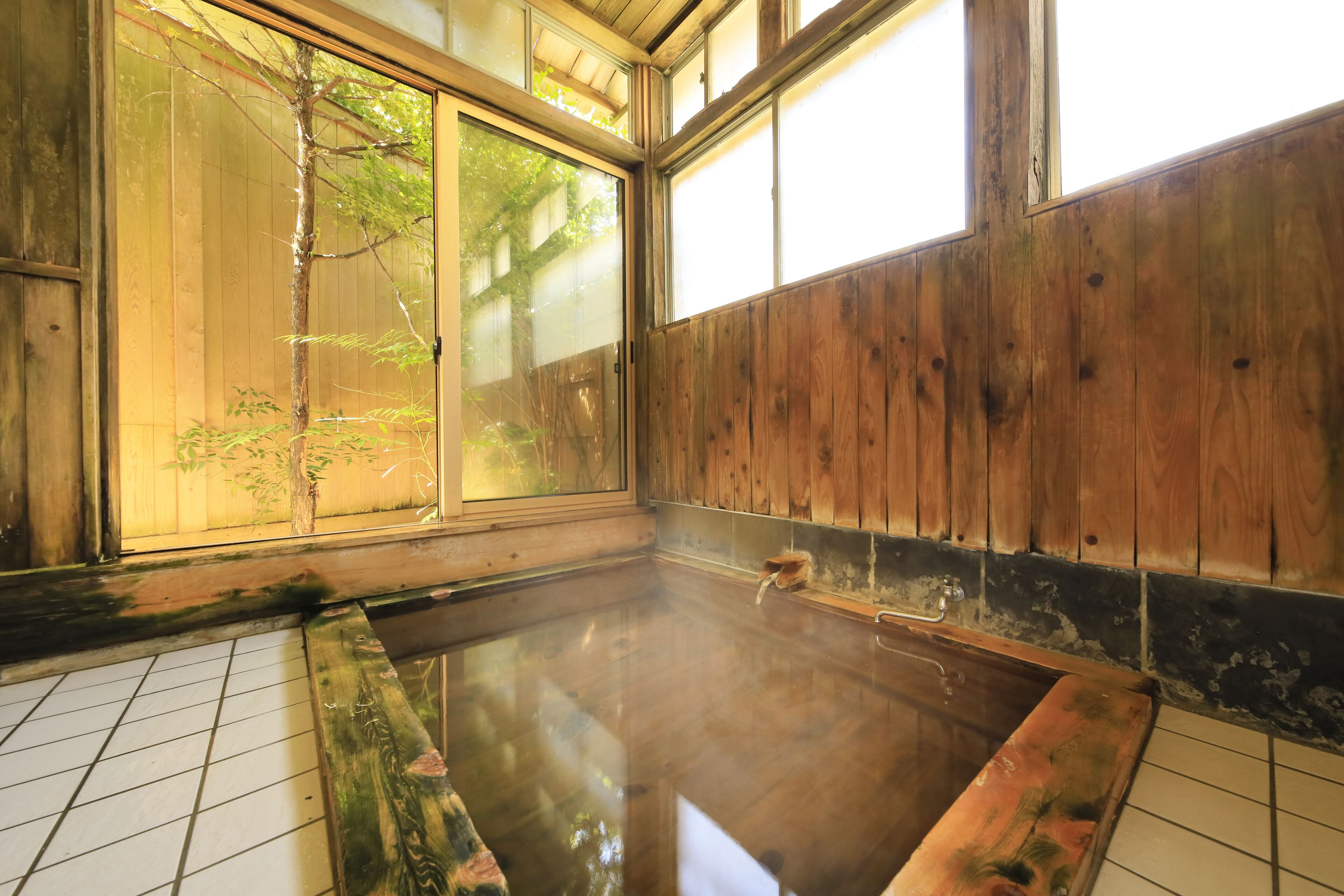 A traditional Japanese onsen with wooden walls and a tiled floor.