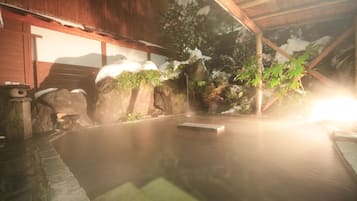 A traditional Japanese onsen with a wooden structure, stone steps, and a hot spring in the center.