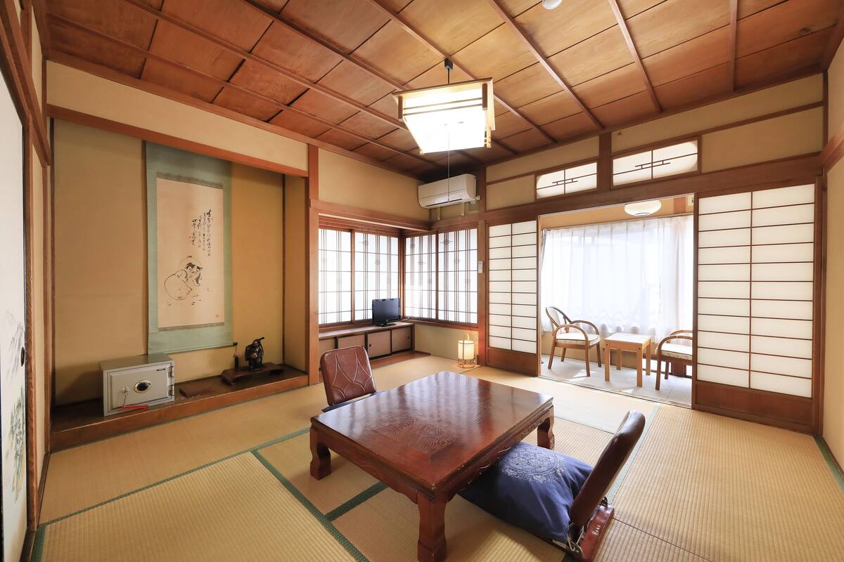 A traditional Japanese room with tatami flooring, a wooden table, and sliding doors.