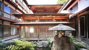 Un edificio japonés tradicional con un estanque de carpas koi, arquitectura de madera y un farol de piedra.