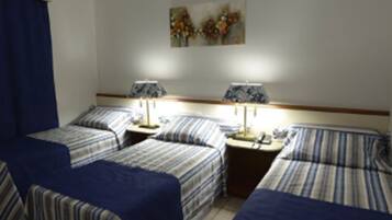 A hotel room with two beds, each with striped bedding, two bedside tables with lamps, and a painting on the wall.