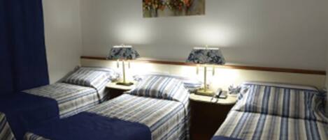 Quarto de hotel com duas camas, cada uma com roupa de cama listrada, duas mesas de cabeceira com abajures e um quadro na parede.