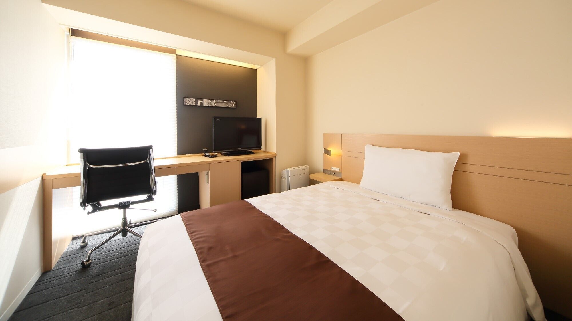 Une chambre d’hôtel équipée d’un lit, d’un bureau avec un ordinateur, d’une chaise et d’un téléviseur.