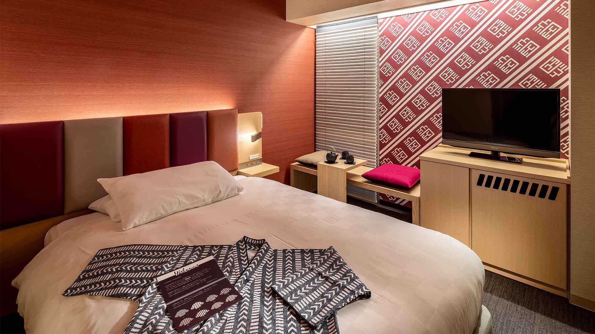 Une chambre d’hôtel équipée d’un lit, d’une télévision, d’un bureau et d’une fenêtre avec des stores.