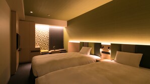 A hotel room with two beds, a television, a window with blinds, and a bedside table.