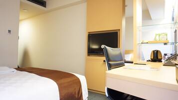 Ein Hotelzimmer mit Bett, Schreibtisch, Stuhl, Fernseher und Ablagefläche mit Toilettenartikeln.