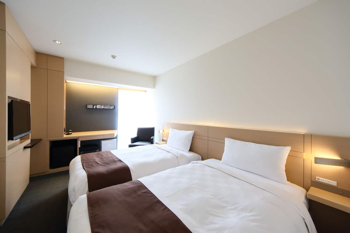 Une chambre d’hôtel avec deux lits, un bureau, une télévision et un design moderne.