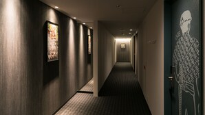 A hallway with dark walls, patterned carpet, and framed artwork.