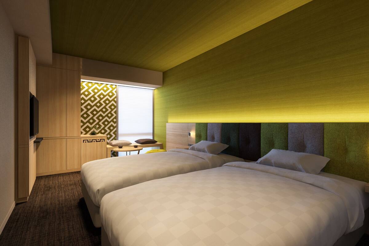 Une chambre d’hôtel avec deux lits, un petit coin salon et un téléviseur.