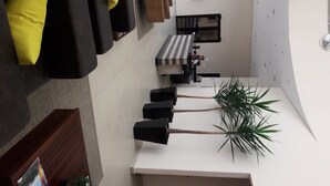 A modern living room with a sofa, a coffee table, and a dining area with a bench and chairs. - Hotel Maruá (São José dos Campos)