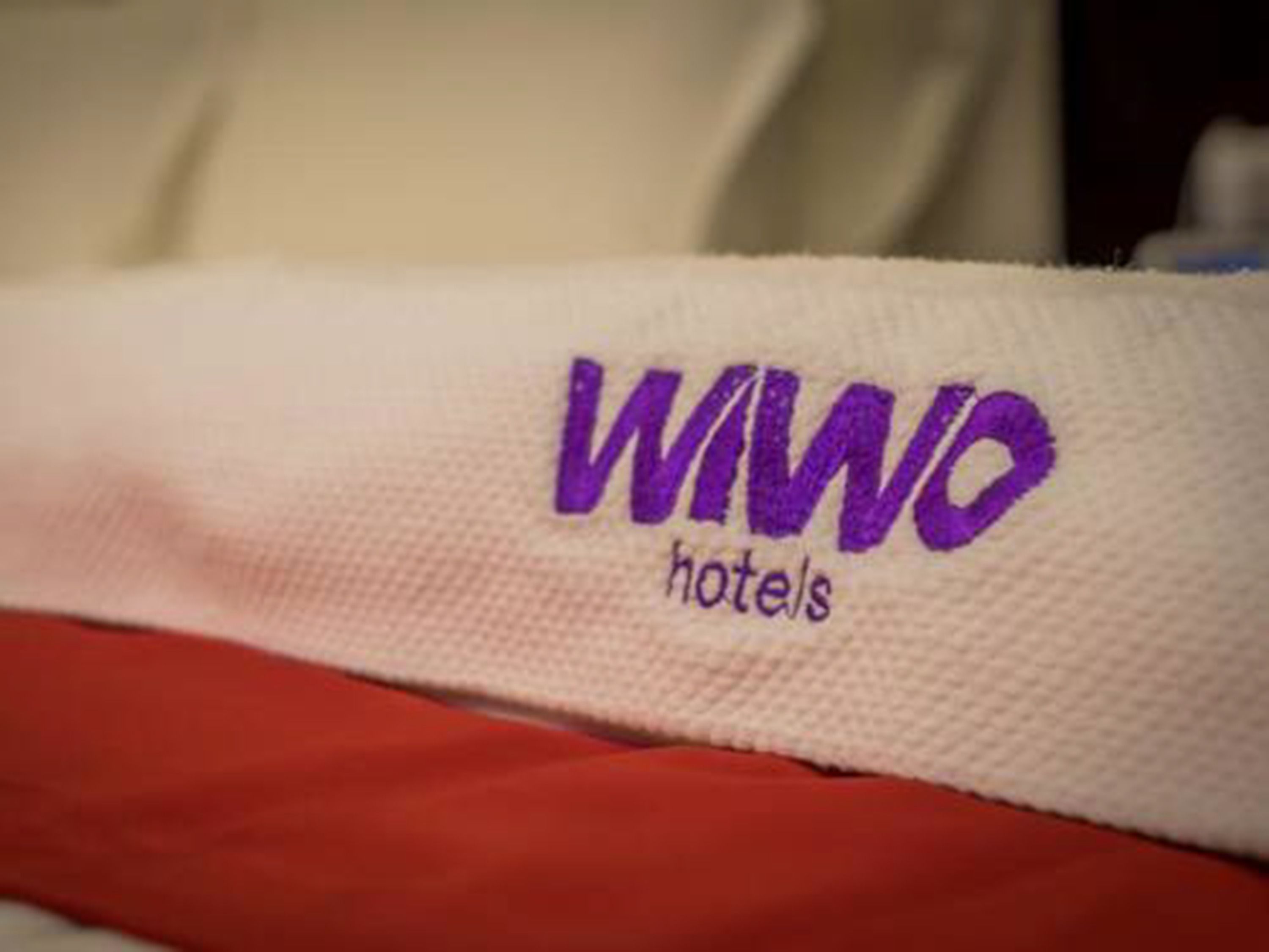 A white fabric with the purple text "WANO hotels" embroidered on it.