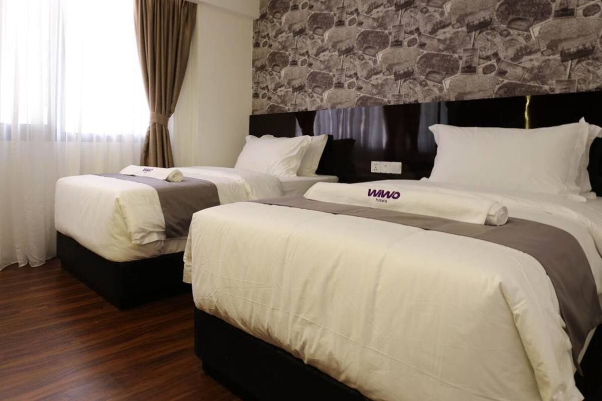Une chambre d’hôtel avec deux lits, un mur décoré d’un motif en pierre et un plancher en bois.