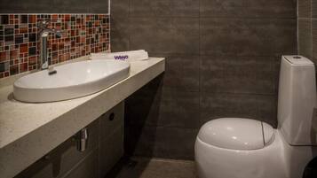 A bathroom with a white sink, a toilet, and a tiled backsplash.