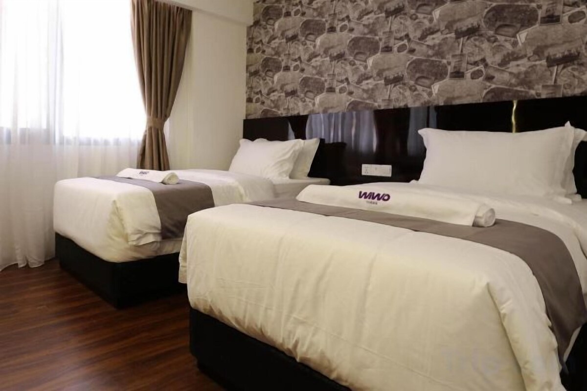 A hotel room with two beds, a stone wall, and a window with curtains.
