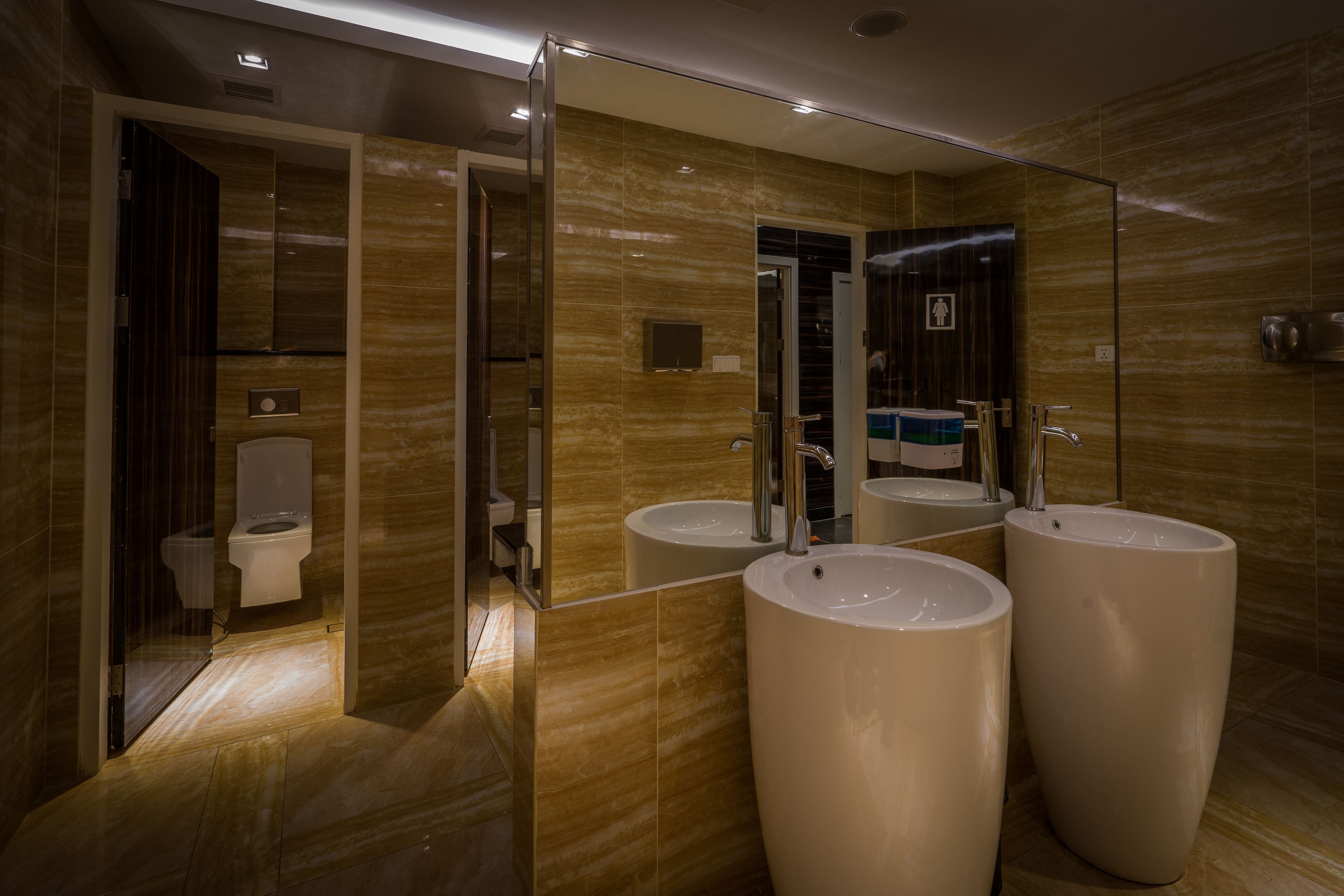 A modern bathroom with a large mirror, two sinks, and a toilet.