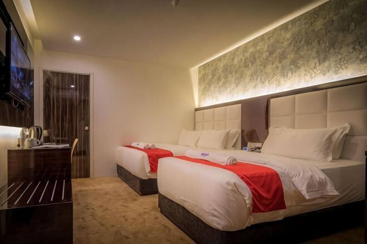 Une chambre d’hôtel avec deux lits, un bureau et une télévision.