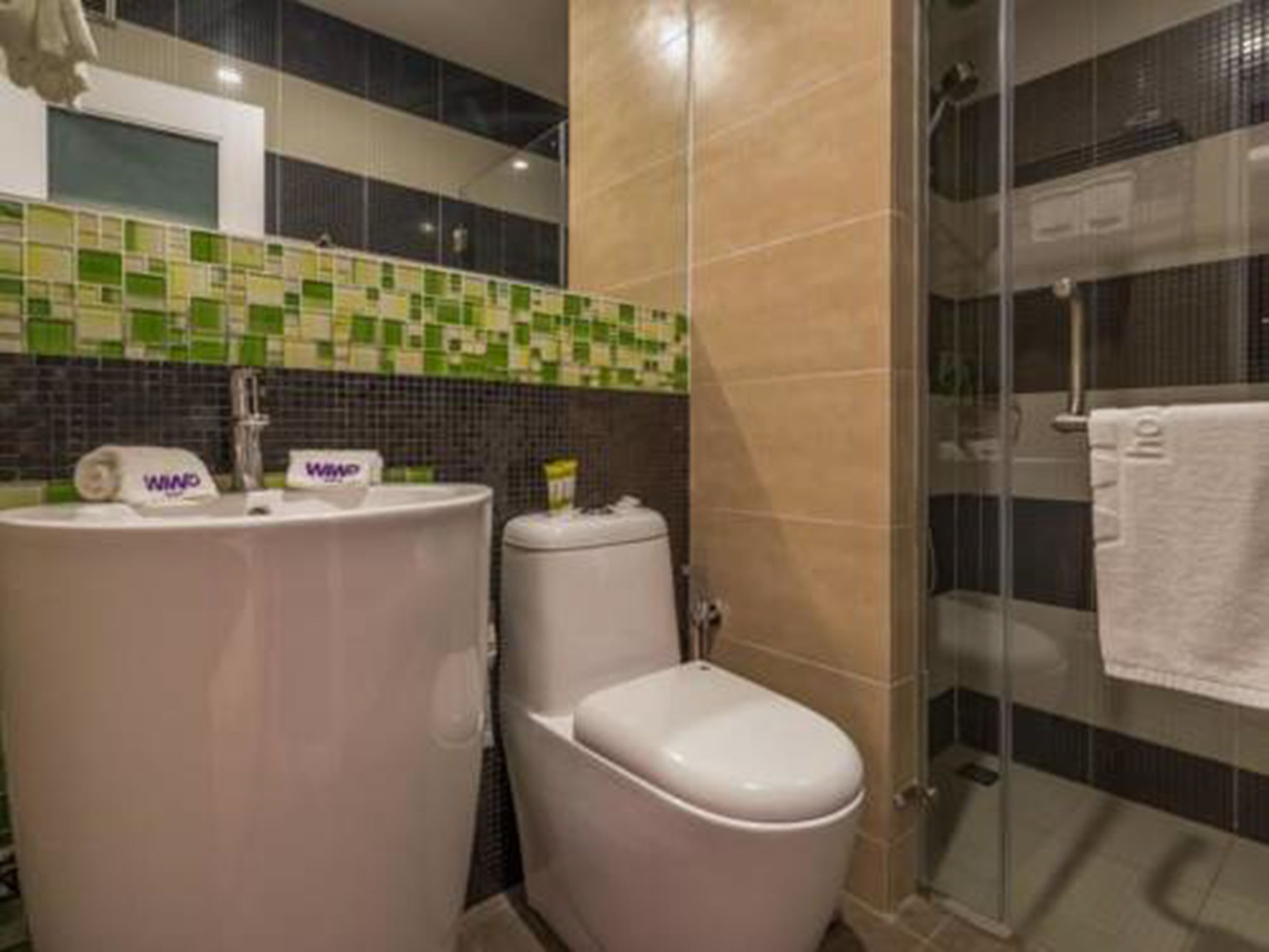 Un baño con lavamanos blanco, inodoro y cabina de ducha de vidrio.
