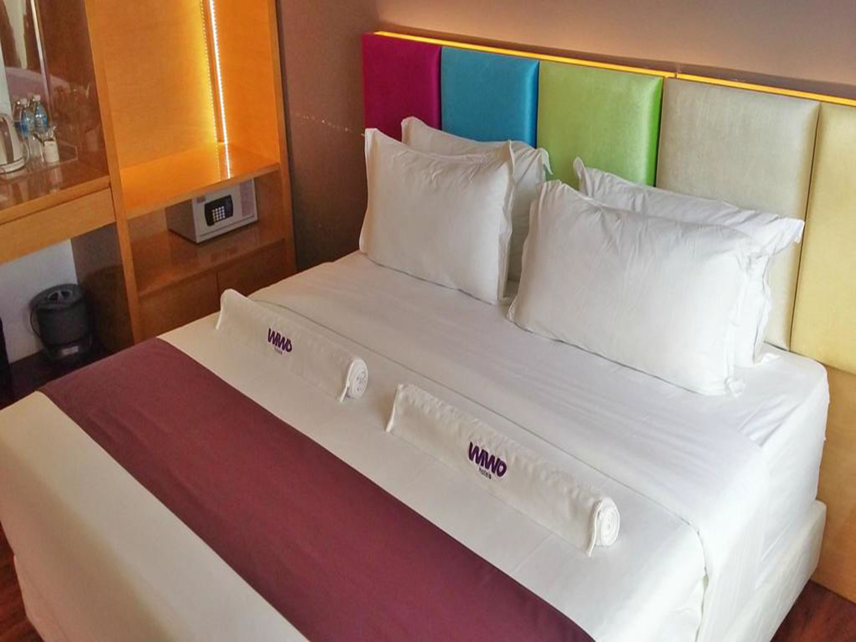 A neatly made bed with white linens and a maroon bedspread.