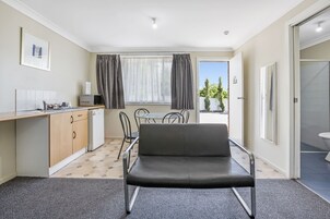 Habitación compacta con kitchenette, una mesa de comedor con sillas, un sofá y vistas al exterior.
