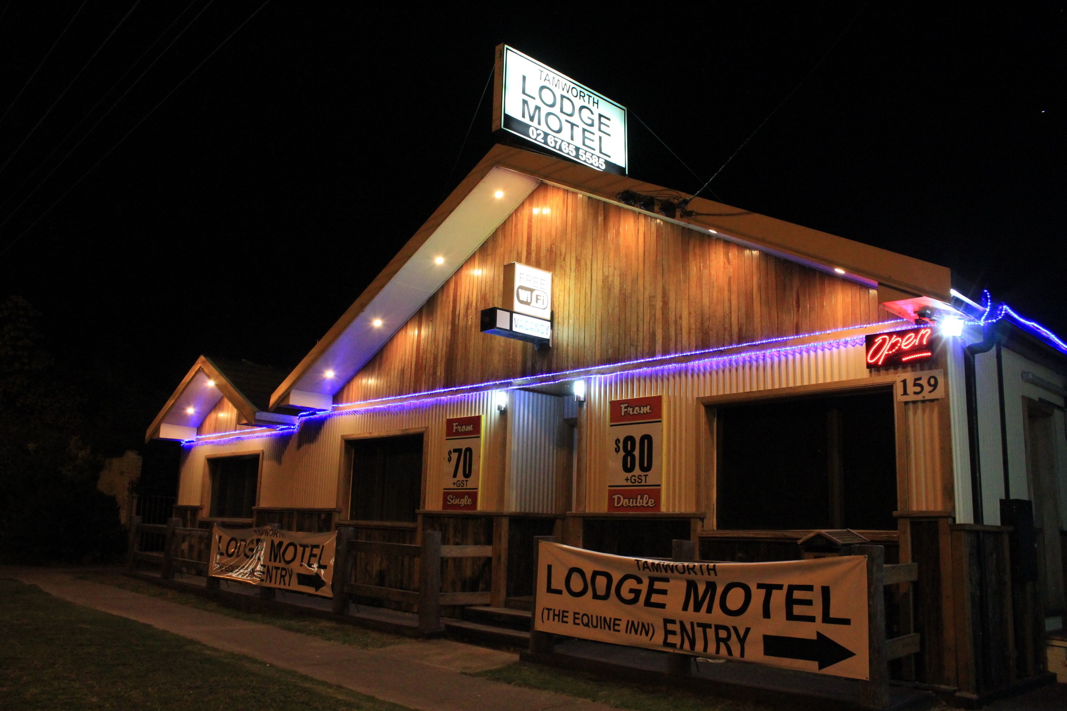 A lodge motel with a rustic wooden facade, illuminated by blue and white lights.