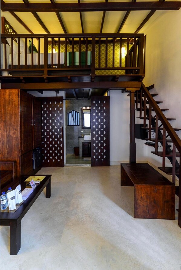 Stunning interior with a high ceiling, wooden staircase, and a bench with a table.