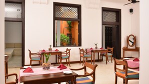 A dining area with wooden tables and chairs, a ceiling fan, and a window with a view of the outdoors. - 56 by Deco (Galle)