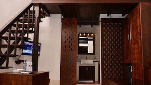 A hotel lobby with a wooden reception desk, a staircase, and a bathroom visible through a wooden partition. - 56 by Deco (Galle)