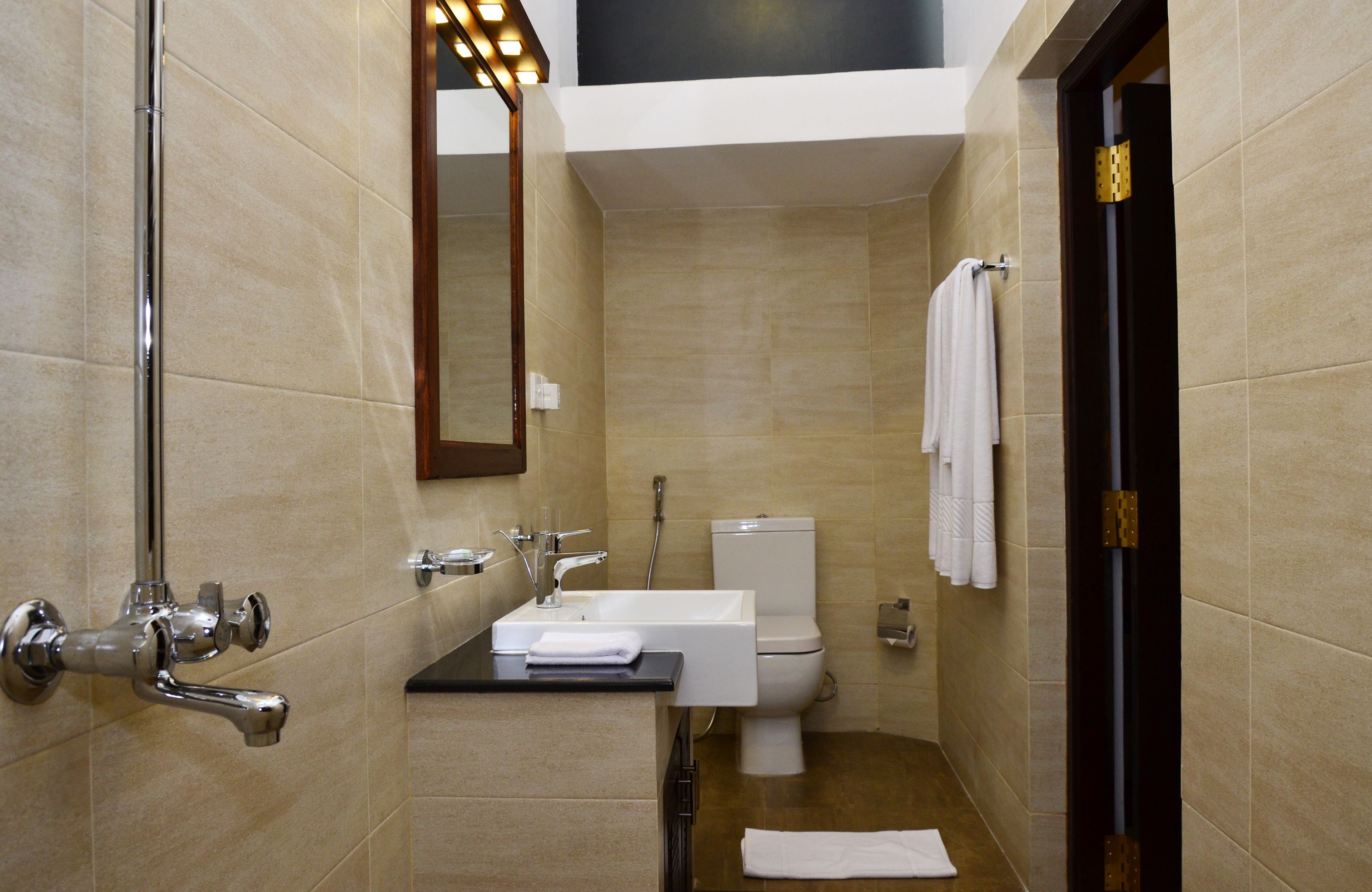 A compact bathroom with a sink, toilet, and shower.