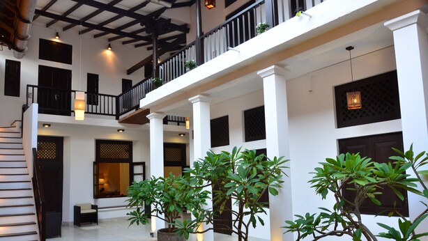 A spacious courtyard with potted plants, a staircase, and a balcony with railings. - 56 by Deco (Galle)