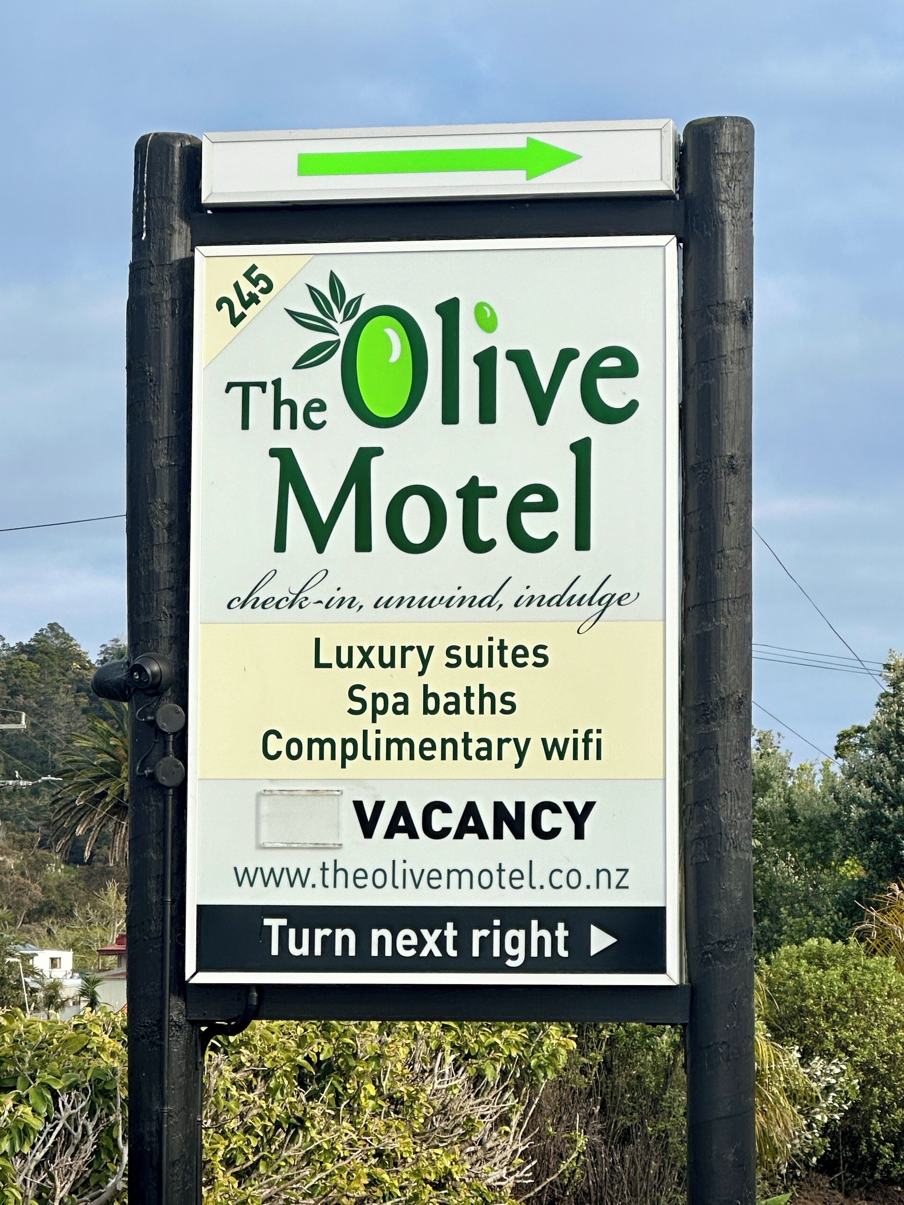 A sign for The Olive Motel advertising luxury suites, spa baths, complimentary wifi, and a vacancy.