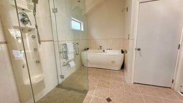 A modern bathroom with a glass-enclosed shower, a white bathtub, and a door.