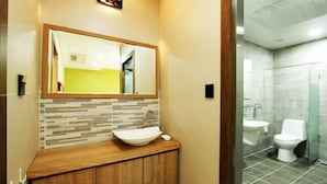 A modern bathroom with a wooden vanity, a large mirror, and a glass shower enclosure. - Benikea Central Hotel (Tongyeong)
