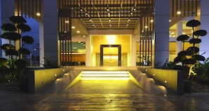 A modern building entrance with a well-lit pathway leading to the door, surrounded by landscaped areas with trees. - V8 Hotel (Johor Bahru)