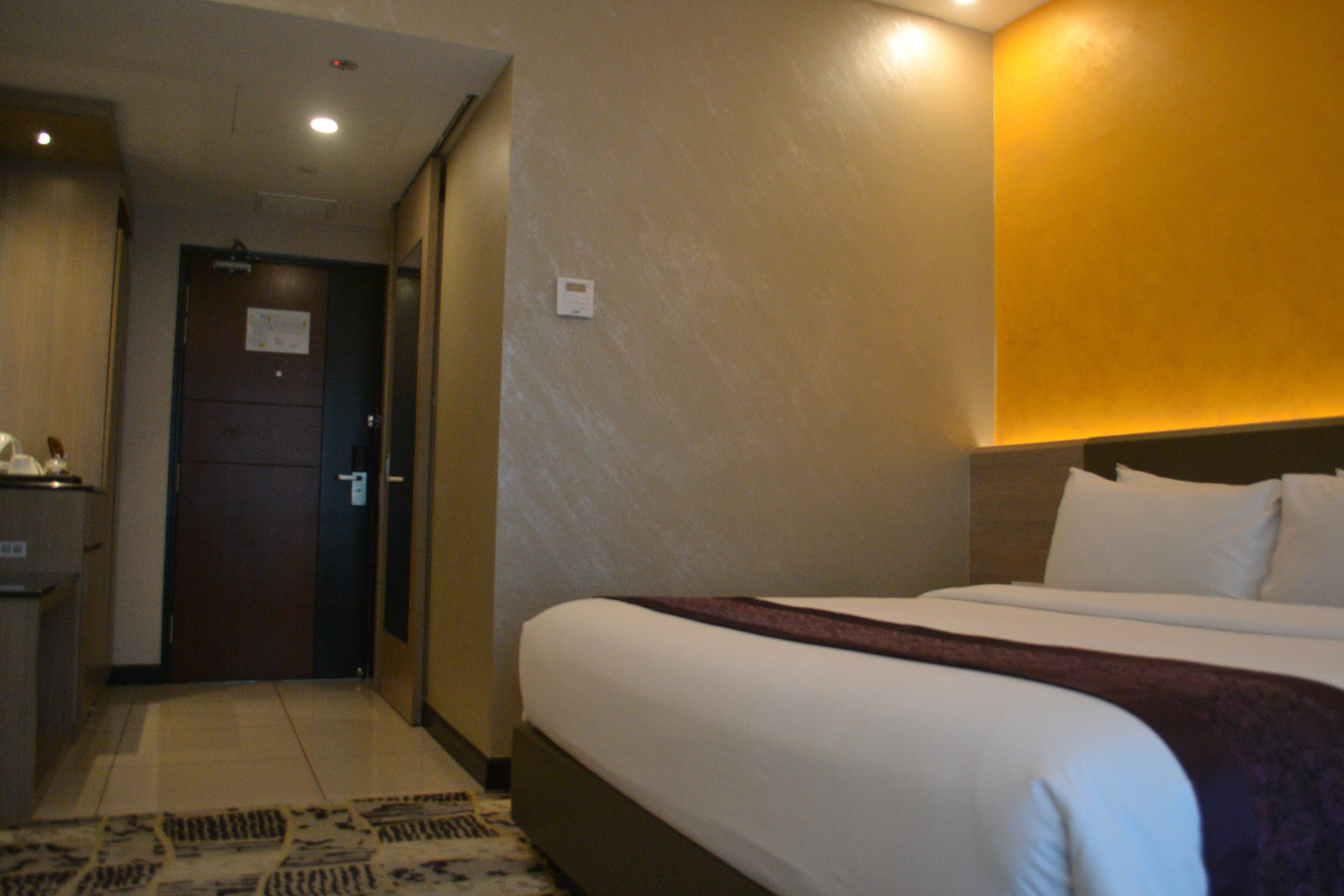 Una habitación de hotel con una cama, un escritorio y una puerta.