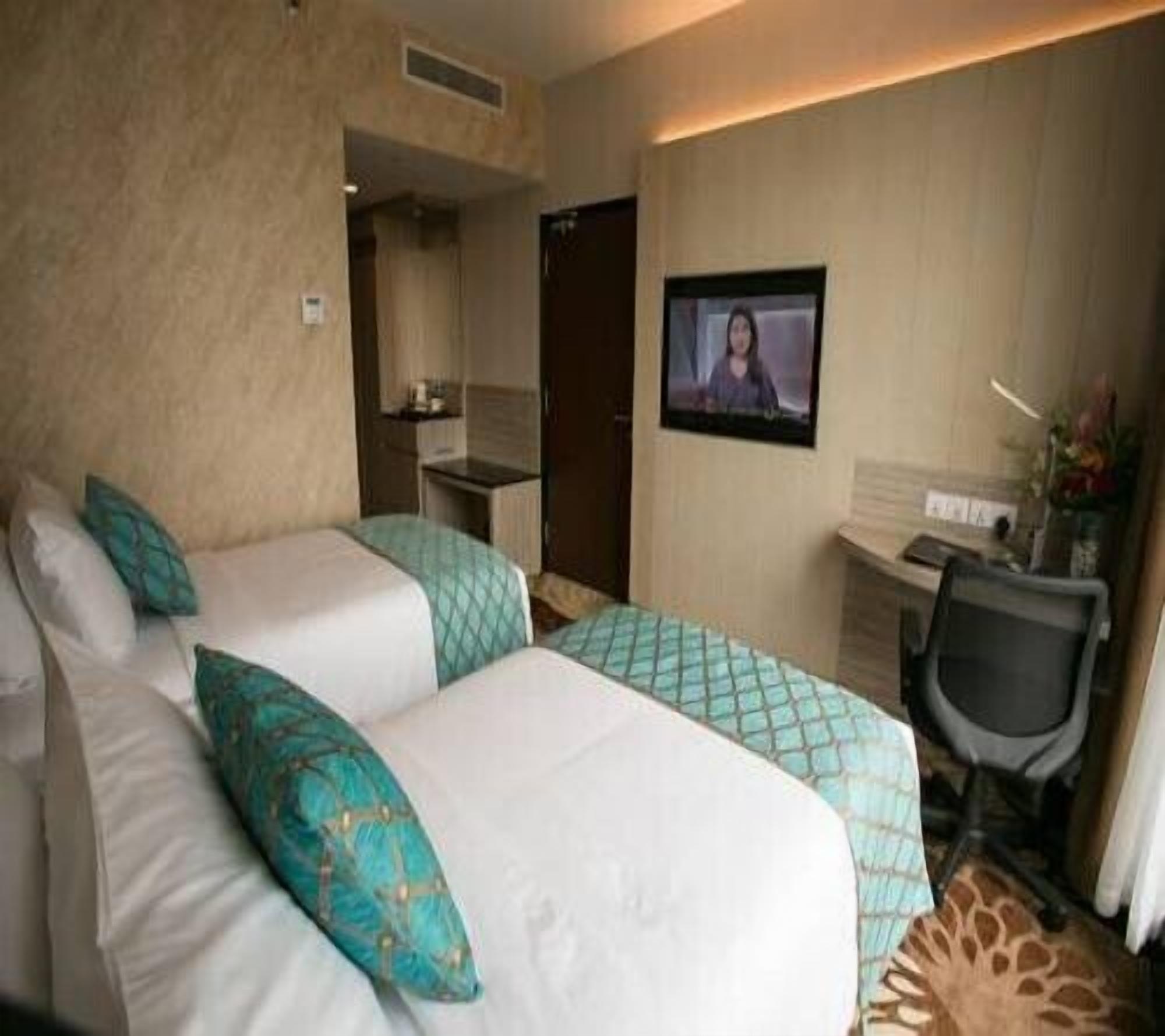 Een hotelkamer met twee bedden, een bureau, een stoel en een televisie.
