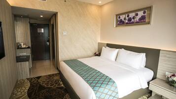 A hotel room with a large bed, a bedside table with a vase of flowers, and a wall-mounted artwork.