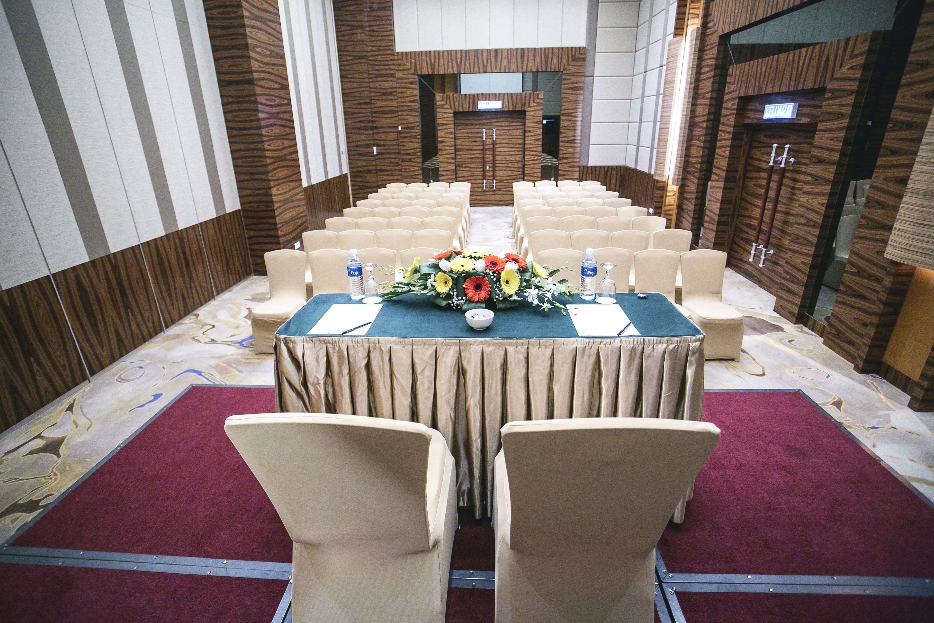 Une salle de conférence avec une longue table, des chaises de couleur beige et un arrangement floral au centre.