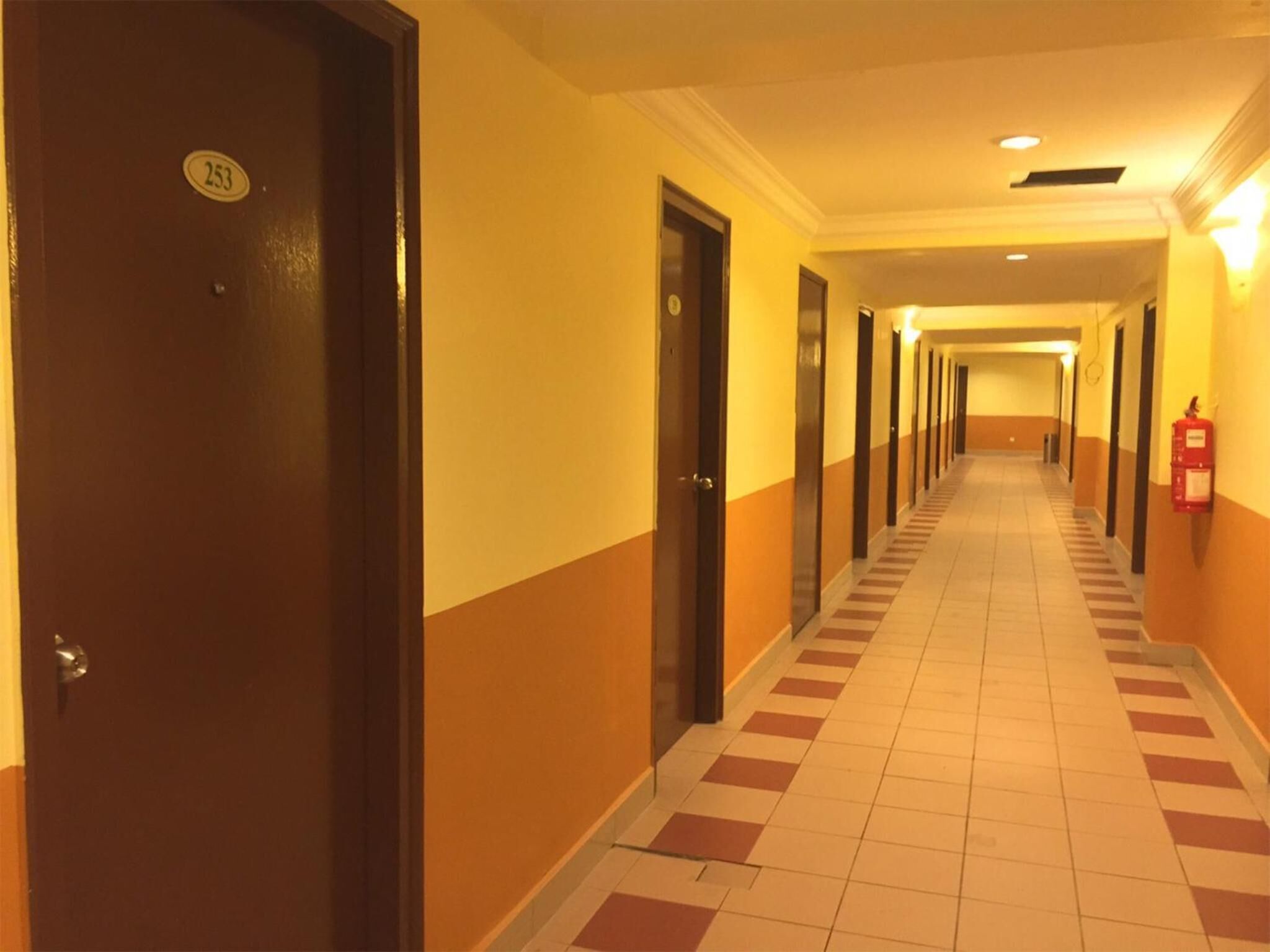 A hotel corridor with doors numbered 253 and 254, a fire extinguisher on the wall, and a tiled floor.