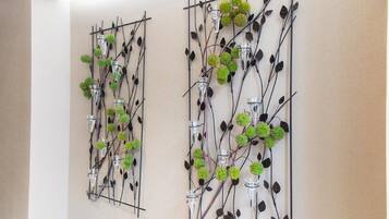 Two wall-mounted decorative panels with glass vases and green foliage.