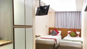 Quarto de hotel com duas camas, televisão fixada na parede e janela com cortinas.
