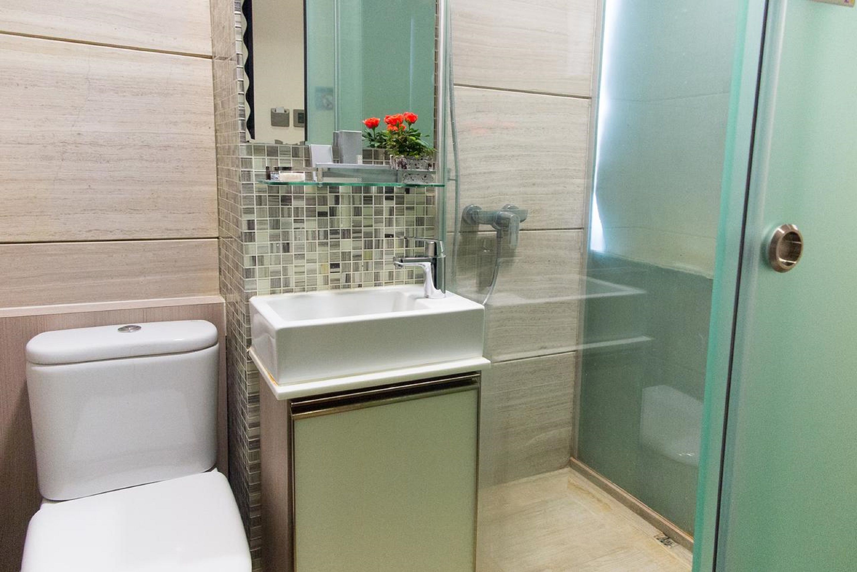 A modern bathroom with a toilet, sink, and glass shower enclosure.