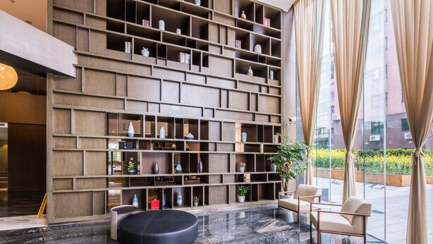 A modern lobby with a large bookshelf, comfortable seating, and a view of the outdoors. - Green Court Residence Jinqiao Diamond Shanghai (Shanghai)