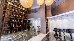 A spacious lobby with a marble floor, a grand piano, and a large bookshelf filled with books and decorative items. - Green Court Residence Jinqiao Diamond Shanghai (Shanghai)