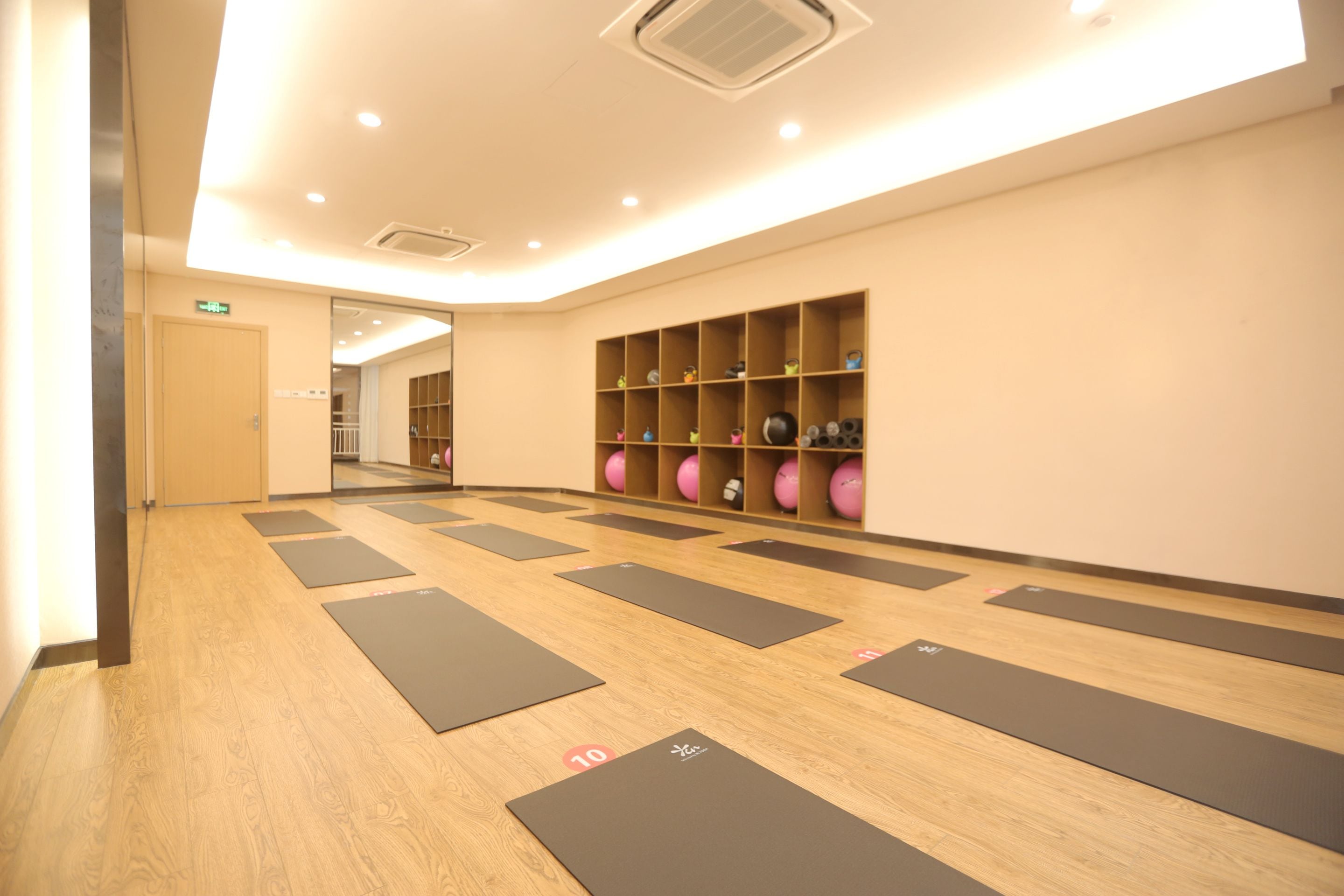 Una palestra con tappetini da ginnastica ed scaffali pieni di palloni.