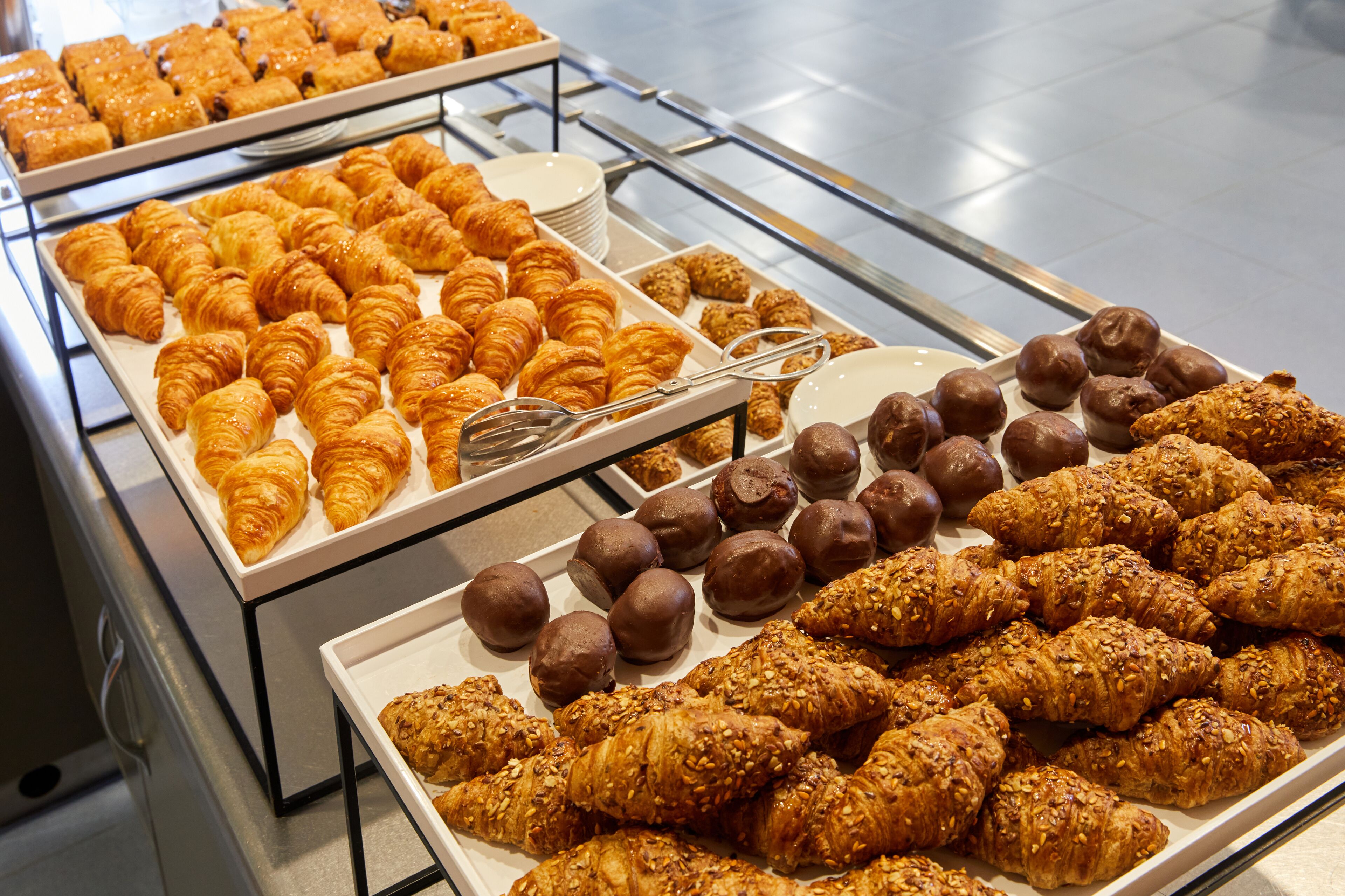 Exibição de diversos doces, incluindo croissants e bolinhos de chocolate.